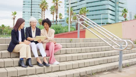 Three businesswomen on stairs looking at tablet