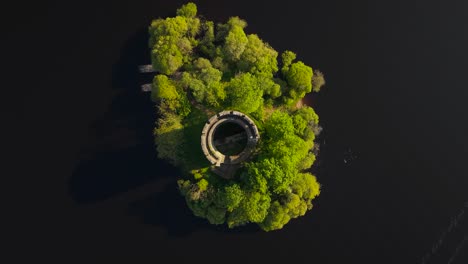cloughoughter castle on a lush green island surrounded by dark water, aerial view