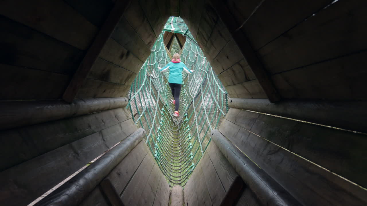 Girls walking and climbing across a rope bridge on an adventure playground