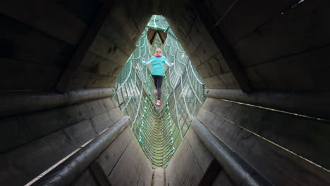 girls walking and climbing across a rope bridge on an adventure playground