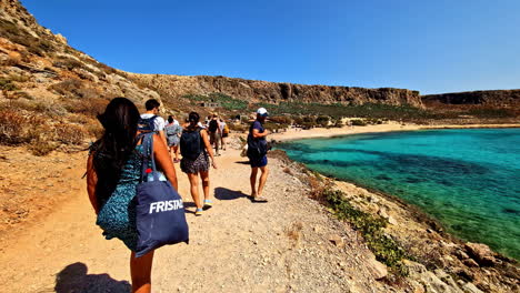 tourists walking along the shores of gramvousa beach during summer in crete, greece. slow motion shot