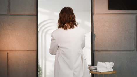 Young-woman-with-red-curly-hair-enjoys-reflection-in-mirror