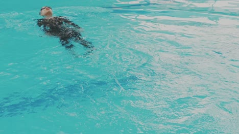 joven nadadora aficionada asiática haciendo ejercicio de espalda en la piscina