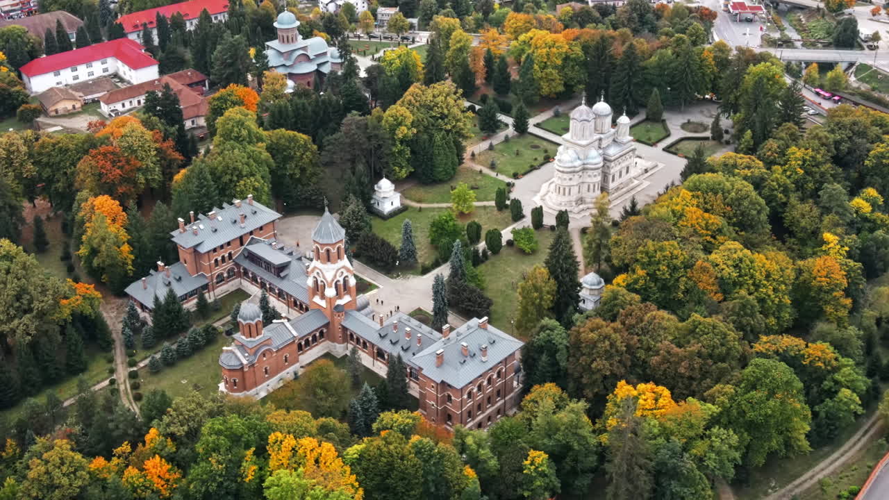 Aerial drone view of The Cathedral of Curtea de Arges, Romania. Episcopal Church, square with greenery and people
