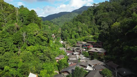 vuelo en cámara lenta sobre un pueblo de montaña escondido en una exuberante jungla verde