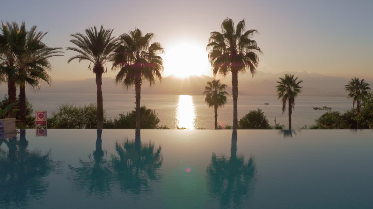escena del complejo con puesta de sol en las montañas y piscina