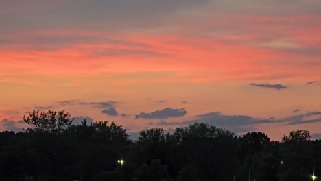 una impresionante vista de una puesta de sol vibrante con nubes coloridas sobre los árboles y el horizonte
