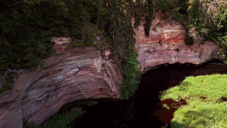 drone footage captures taevaskoja with its dramatic sandstone cliffs flowing river and dense green forest creating one of estonia’s most stunning natural landmarks and scenic outdoor destinations