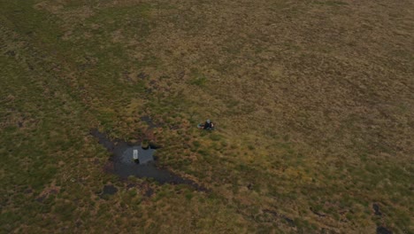 Aerial-footage,-Man-sitting-on-top-of-mountain-enjoying-the-view,-happiness-at-peace