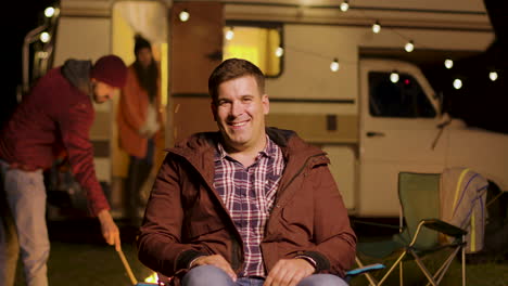 happy young man sitting on camping chair looking at the camera