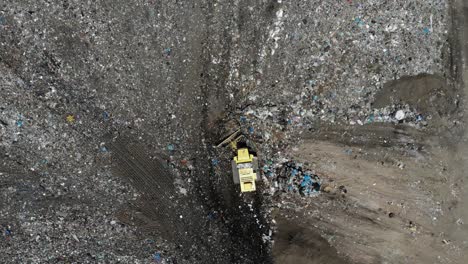 Bulldozer-pushing-garbage-on-a-landfill---aerial-view