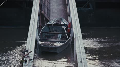 small boat tied to a ramp, partially submerged in murky floodwaters at night