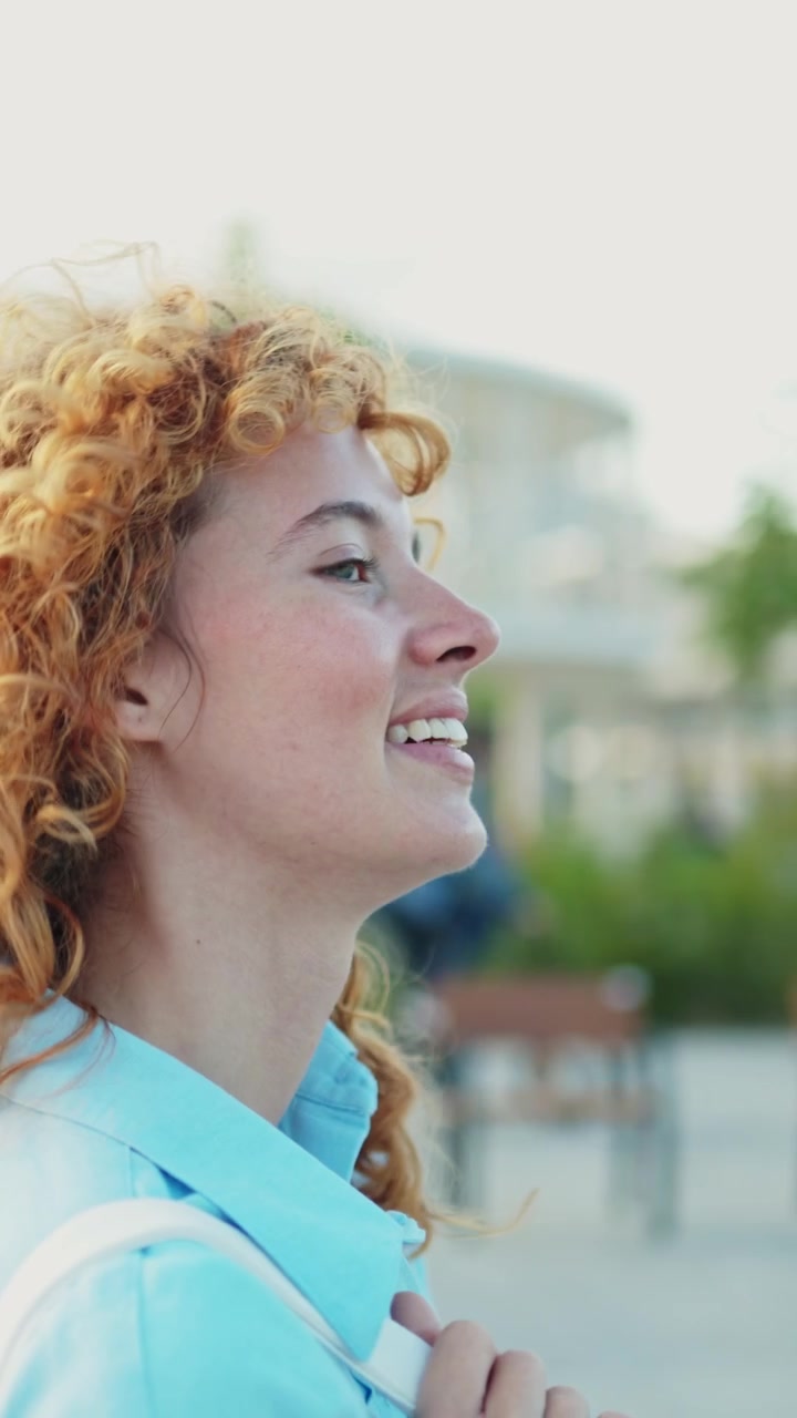 Peaceful Young Woman with Curly Red Hair Smiling Outdoors