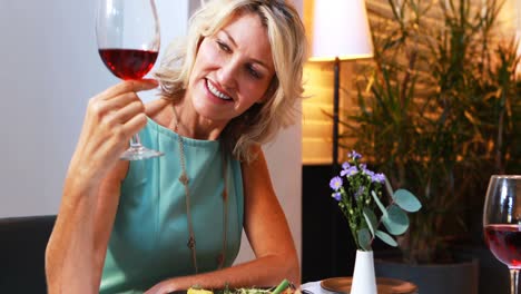 mujer madura sonriente bebiendo vino tinto