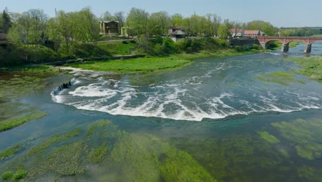Aerial-establishing-view-of-Vimba-fish-,-Kuldiga,-sunny-spring-day,-wide-drone-shot-moving-forward