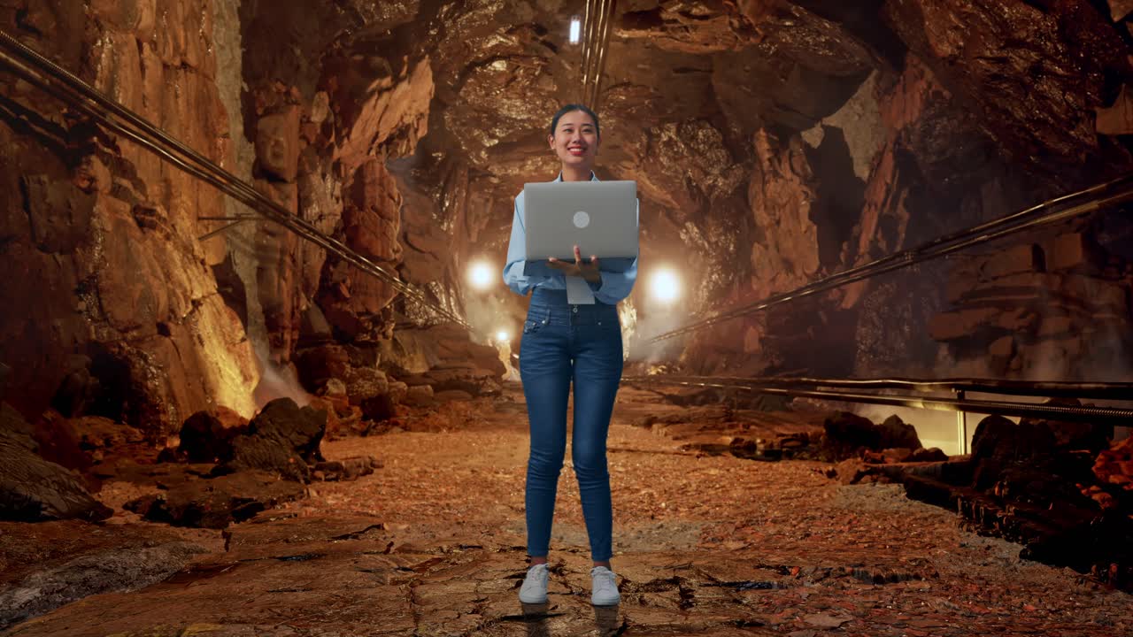 Full Body Of Asian Female With Her Laptop In Underground Mine Tunnel, She Observes By Looking Around Before She Come To Concentrating With Her Laptop