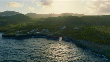 vista aérea del famoso arco natural la hondonada y las villas de lujo en el acantilado durante la puesta de sol dorada en el fondo - samana, república dominicana - toma amplia