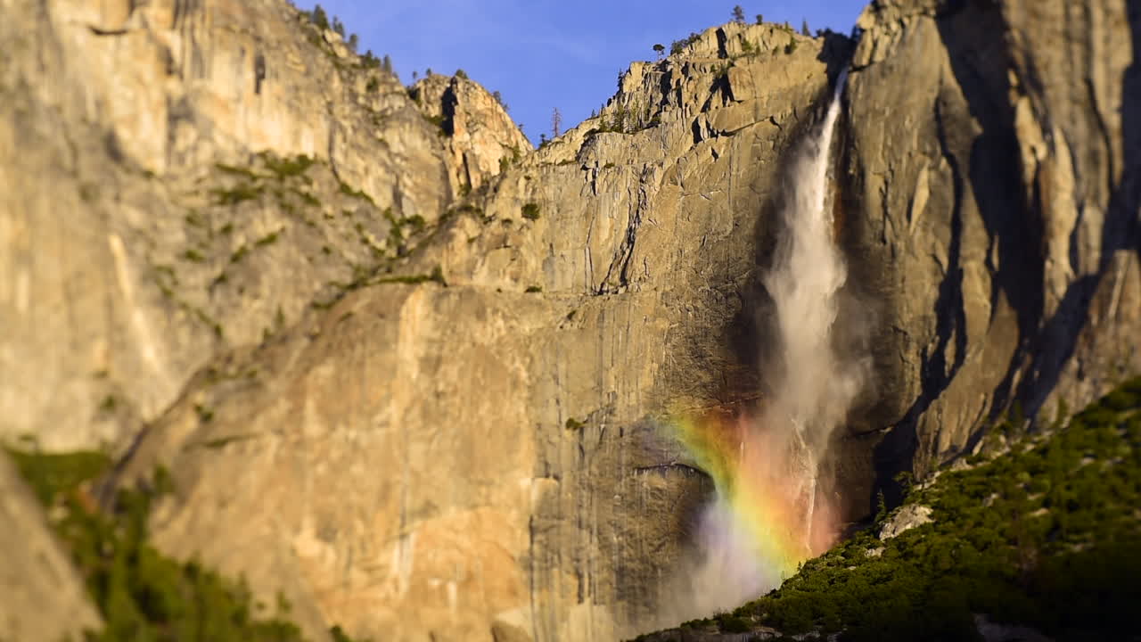 Ultra slow motion of Yosemite Falls waterfall in the sunlight causing a stunning rainbow in the spray - Yosemite National Park