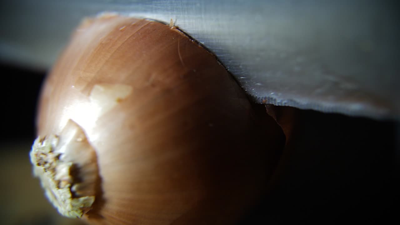 Close-up of a Hand Slicing a Fresh Onion with a Knife