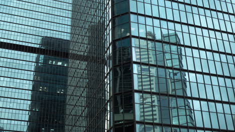 modern walls are made of glass and steel with reflections of buildings and blue sky