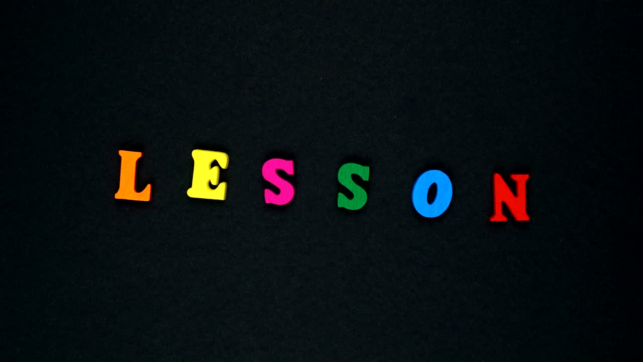 Parola "lezione" formata da lettere di legno multicolori. Loop di parole colorate.