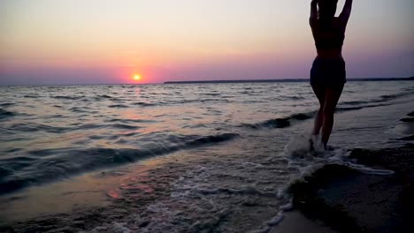 Girl-walking-on-the-sunset-beach-in-front-of-waves-on-the-sea