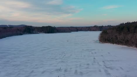 Langsam-Rückwärts-Von-Zwei-Eisfischern-Wegfliegen,-Die-Auf-Einem-Zugefrorenen-See-Spazieren-Gehen