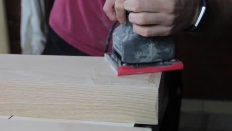 Finish-sanding-the-wood-filler-on-wooden-floating-shelves-in-preparation-to-be-stained-and-hung-in-a-remodeled-bathroom