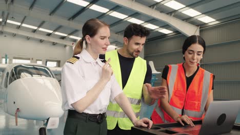 pilot and mechanics discussing airplane maintenance in a hangar