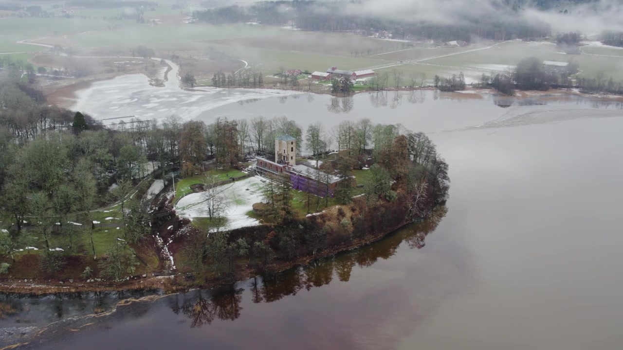 Veduta aerea delle rovine del castello di Grafsnas su una penisola boscosa circondata dall'acqua in inverno