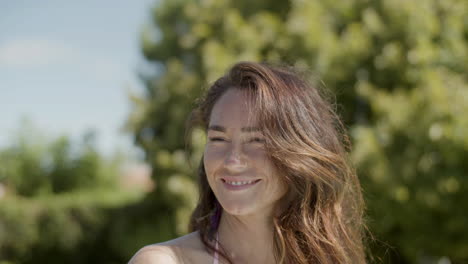 close up of smiling woman in bikini smiling, drinking and clinking glass into camera