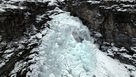 pullback on frosted waterfall from rugged cliffs during winter in northern norway