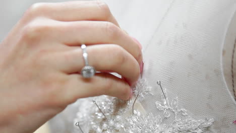 Close-up-fashion-designer-for-brides-in-his-Studio-pins-needles-lace-wedding-dress.-Seamstress-creates-an-exclusive-wedding-dress.-Secure-with-pins-and-needles-outline.-Small-private-business