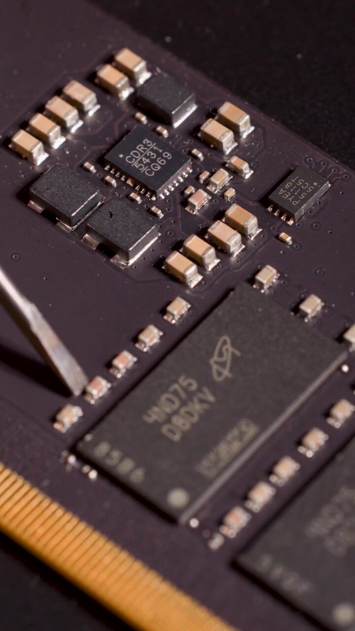 Nærbillede af håndværktøj, der peger på mikrochip på printplade, med lav dybdeskarphed og stabilt kamera