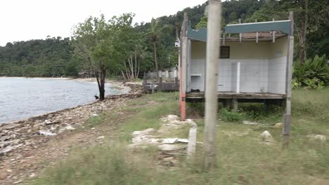 toma de camión a la derecha en movimiento de un complejo de bungalows de playa destruido abandonado con palmeras oceánicas y bungalows descompuestos por los efectos del covid 19 en el turismo