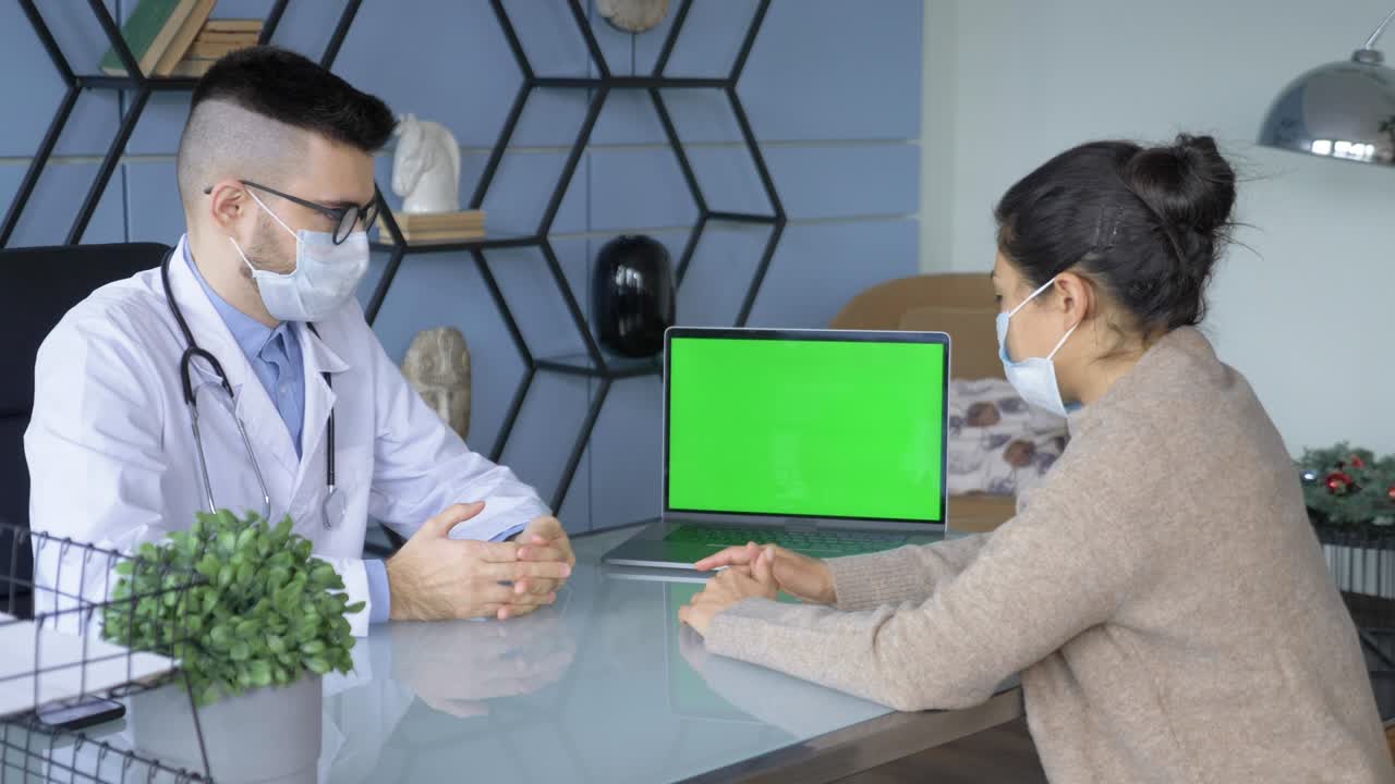 가족 의사는 건강 클리닉에서 녹색 화면을 가진 컴퓨터에서 고령 환자에게 진단을 설명하고 있습니다. 색 실험실 코트를 입은 조교는 병원 사무실에서 의학 역사를 읽고 있습니다.