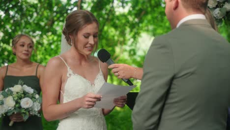 bride reads her vows from a paper smiling and laughing at groom during ceremony