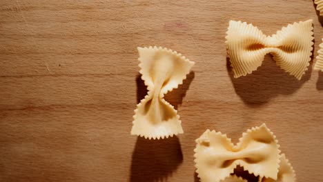 throwing uncooked butterfly pasta onto a wooden table close up in studio lighting