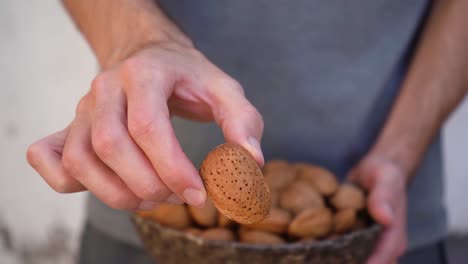 hombre mostrando almendras con cáscara en la cámara