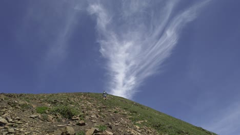 hiker ascending mountain sky tilt clouds, rockies, kananaskis, alberta canada