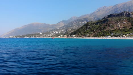 blue azure sea water surrounding beautiful coastline with green hills and mountains in south albania