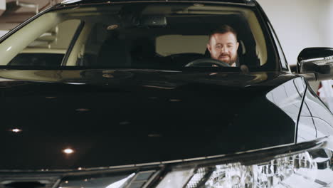 hombre conduciendo e inspeccionando un coche negro