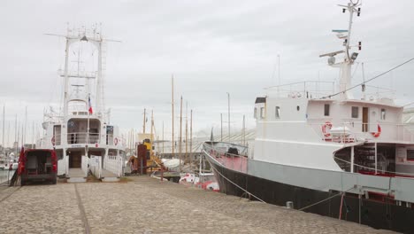 boats docked at a cobblestone pier in a harbor