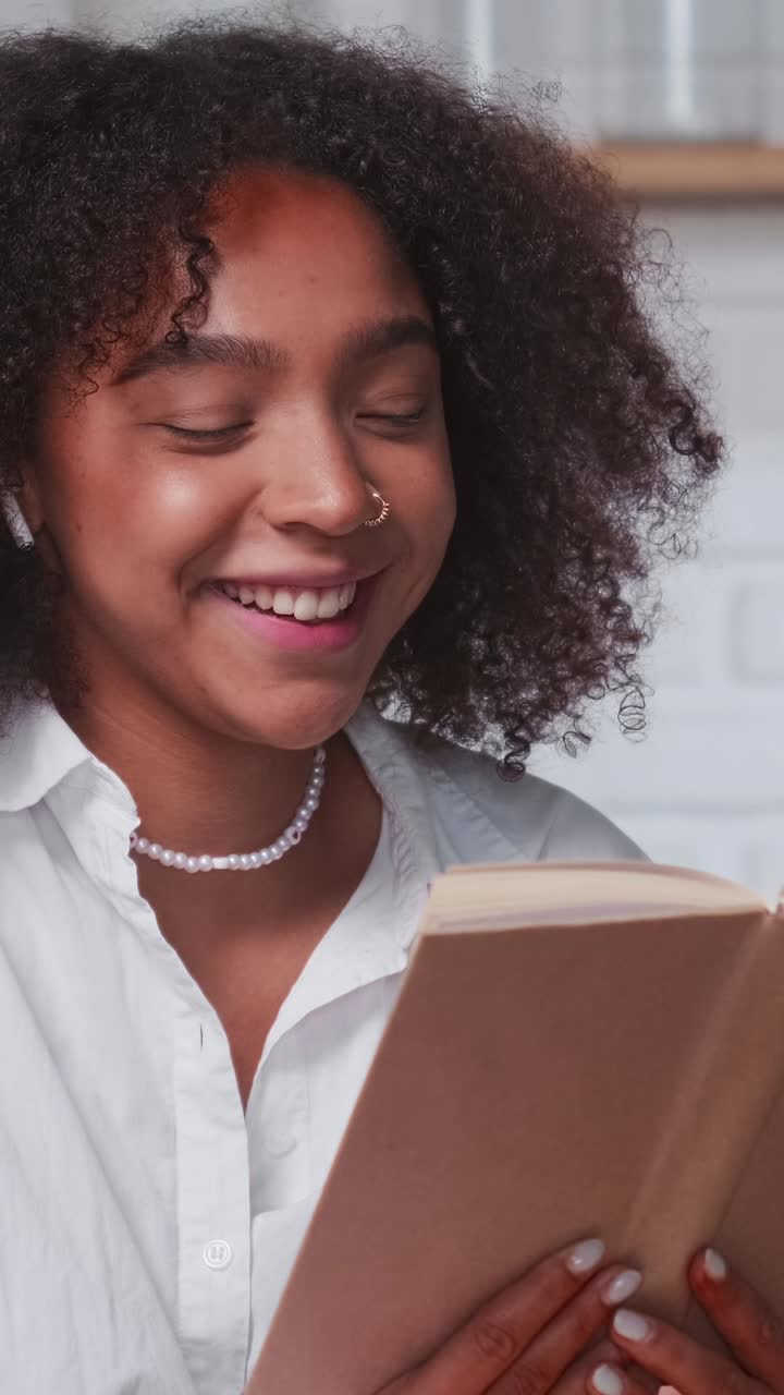 Young laughing attractive african american woman reading book with jokes