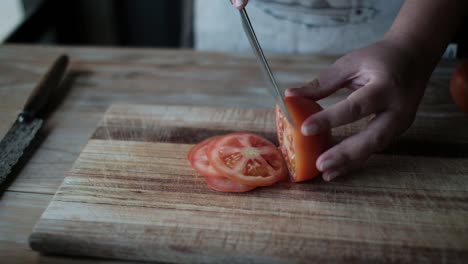 cook cuts tomato into thin slices with knife