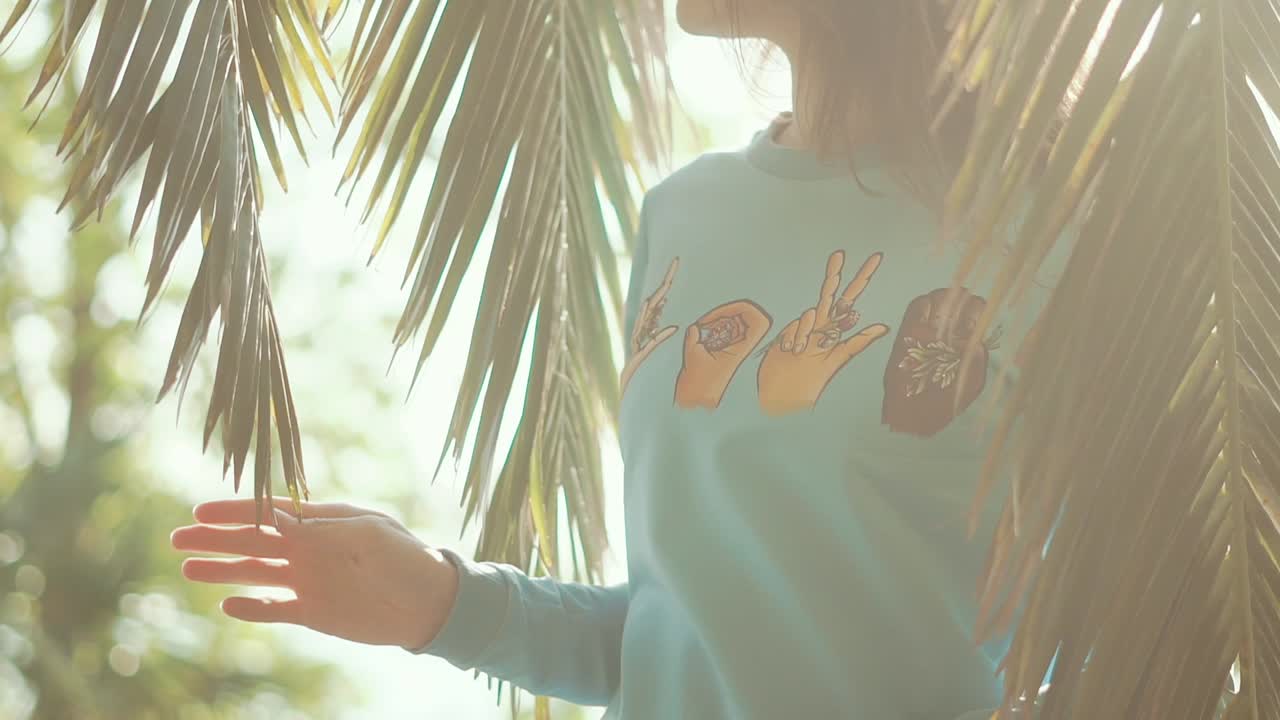 mujer con un suéter bajo palmeras