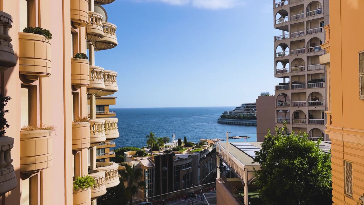 Vista soleggiata del Mar Mediterraneo incorniciata da eleganti condomini e balconi a Monaco, che mostra l'architettura costiera di lusso e la vita in Riviera