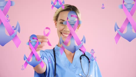 Animation-of-pink-ribbon-and-anchor-logos,-floating-over-smiling-female-doctor-holding-pink-ribbon