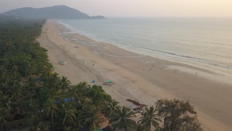 aerial flyover of tropical palm lined misty agonda beach in goa, india