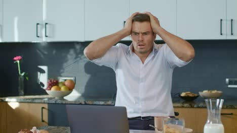 hombre asustado viendo video en una computadora portátil en una casa de lujo. hombre de negocios en shock